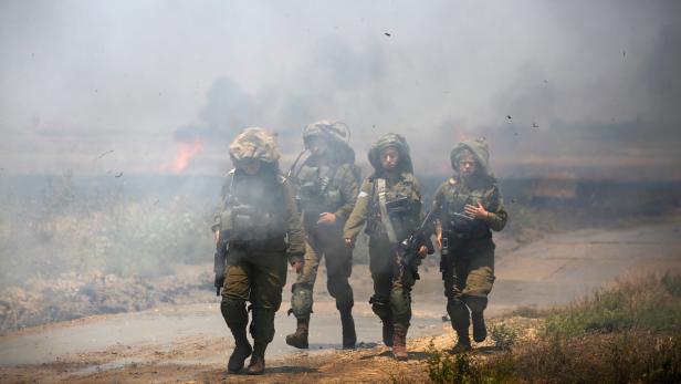 Israelische Soldaten vor einem brennenden Feld nahe der Grenze von Israel und Gaza.