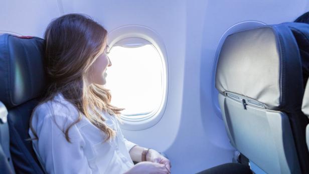 Junge Frau sitzt im Flieger.
