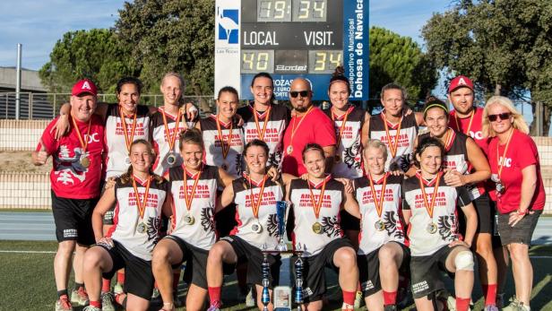 Das österreichische Flag-Football-Team posiert mit Medaillen und Pokalen vor einer Anzeigetafel.