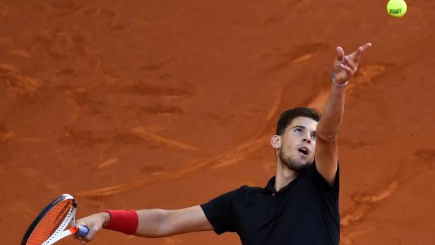 Ein Tennisspieler beim Aufschlag auf einem Sandplatz.