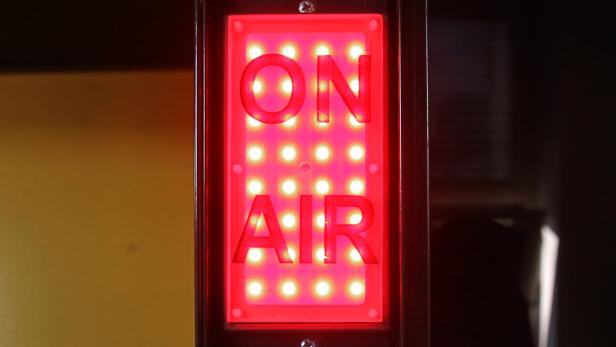 Ein rotes „On Air“-Schild leuchtet.