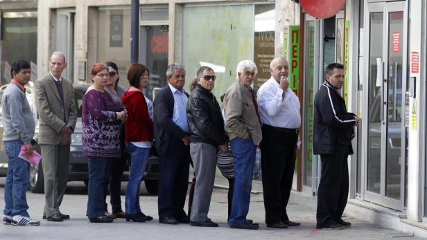 Depositors wait for the opening of a branch of Laiki Bank in Nicosia March 29, 2013. Cyprus has &quot;contained&quot; the risk of bankruptcy in the wake of a tough rescue package with the European Union and has no intention of leaving Europe&#039;s single currency, the island&#039;s president said on Friday. Conservative leader Nicos Anastasiades assured Cypriots and wealthy foreign depositors that restrictions on bank transactions, imposed this week, would gradually be lifted, but gave no time frame. REUTERS/Bogdan Cristel (CYPRUS - Tags: BUSINESS POLITICS)