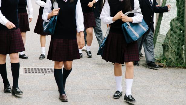 Japanese high school. School children walk outside, unrecognisable, school uniform