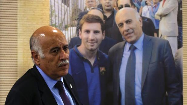 Ein Mann steht vor einem Plakat mit einem Foto von Lionel Messi.