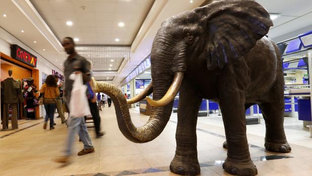 A shopper walks past an elephant figure representing the Nakumatt supermarket within the Village market complex mall, in Nairobi