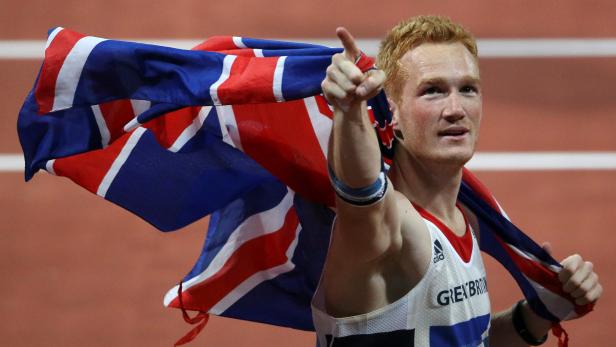 FILE PHOTO: Britain's Greg Rutherford gestures as he holds a Union flag behind him after winning the men's long jump final at the London 2012 Olympic Games at the Olympic Stadium