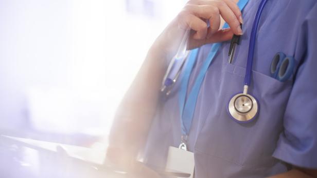 Eine Krankenschwester mit Stethoskop und Stift in der Tasche hält ein Tablet.