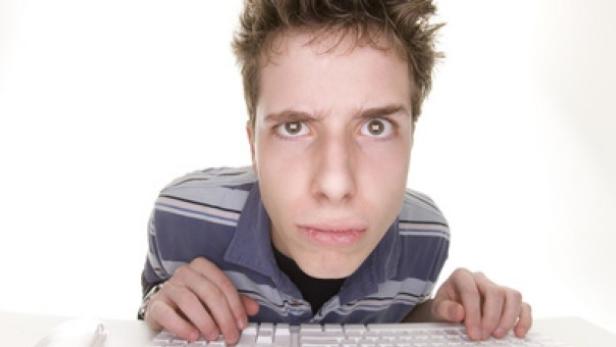 Ein junger Mann schaut mit besorgtem Gesichtsausdruck auf einen Computerbildschirm.