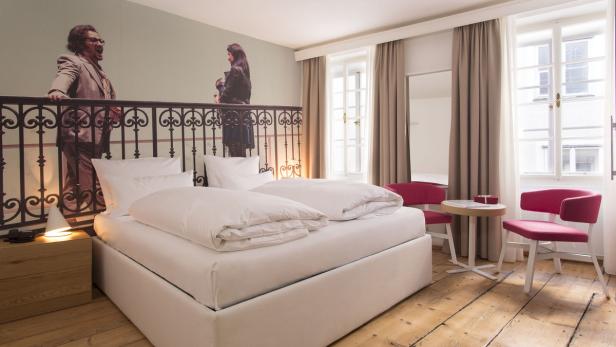 Ein Hotelzimmer mit einem Doppelbett und einem Wandbild von zwei Schauspielern.