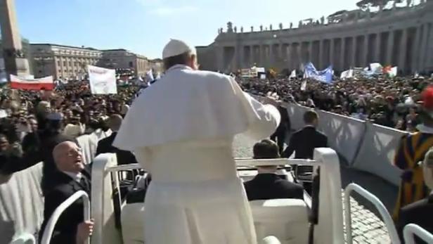 Papst Franziskus winkt einer Menschenmenge auf dem Petersplatz zu.