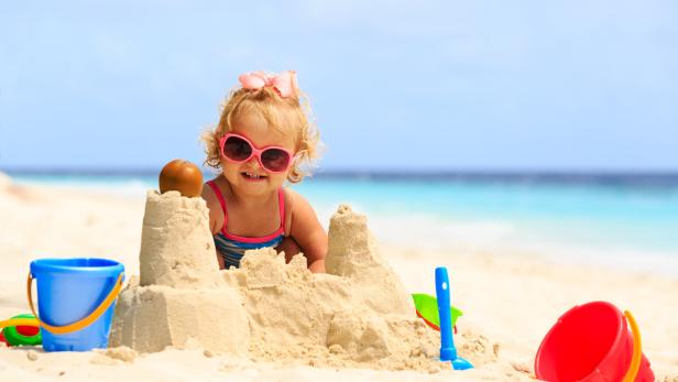 cute little girl playing with sand on beach