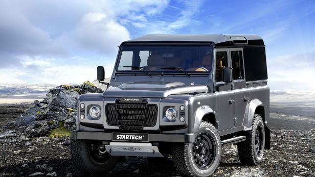 Ein grauer Land Rover Defender mit Startech-Zubehör auf einem steinigen Feldweg.