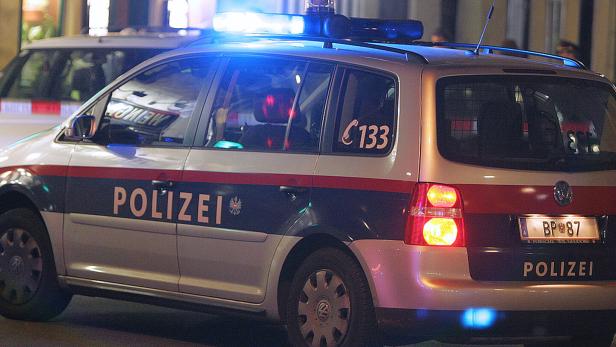 Ein silbernes Polizeiauto mit Blaulicht steht auf der Straße.