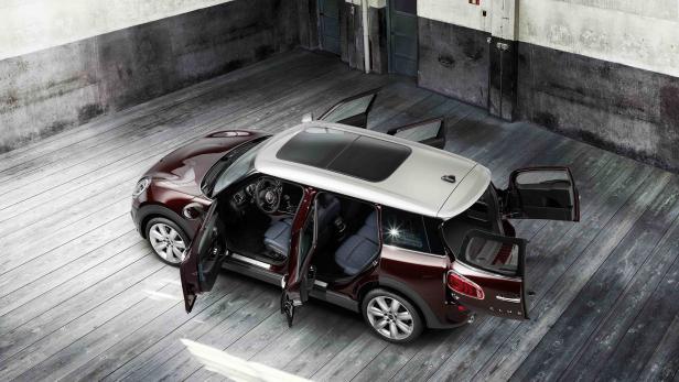 Ein burgunderroter Mini Clubman mit geöffneten Türen steht in einer Lagerhalle.