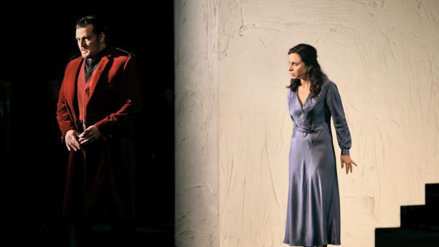 Ein Mann in einem roten Mantel und eine Frau in einem blauen Kleid stehen auf einer Bühne.