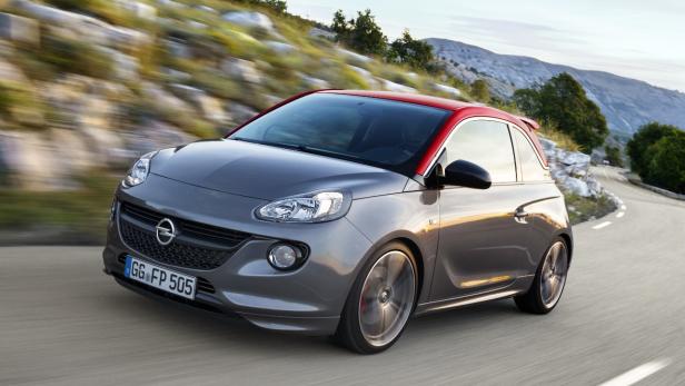 Ein grauer Opel Adam mit rotem Dach fährt auf einer kurvigen Straße.