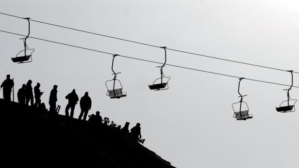 Silhouetten von Skifahrern unter einem Sessellift.