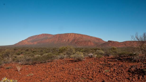 Eine rote Hügellandschaft unter einem klaren, blauen Himmel.