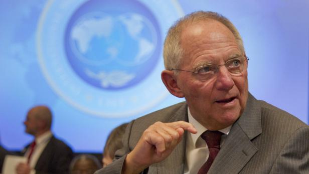 Wolfgang Schäuble spricht vor einem blauen Hintergrund mit einem Weltkugel-Logo.