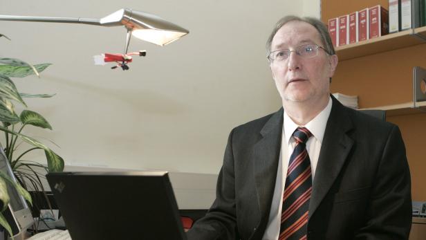 46-19169043 Ein Mann im Anzug sitzt an einem Schreibtisch mit Laptop und Büromaterialien.