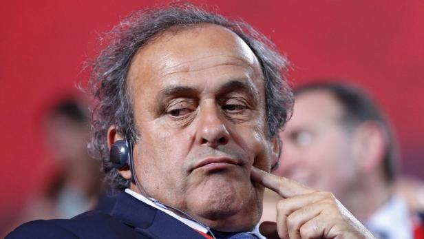 Michel Platini mit einem Headset, nachdenklich mit dem Finger am Kinn.