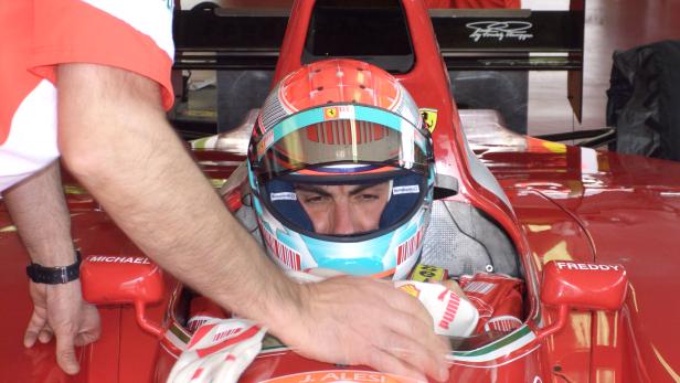 Jean Alesi sitzt in seinem roten Ferrari-Rennwagen.