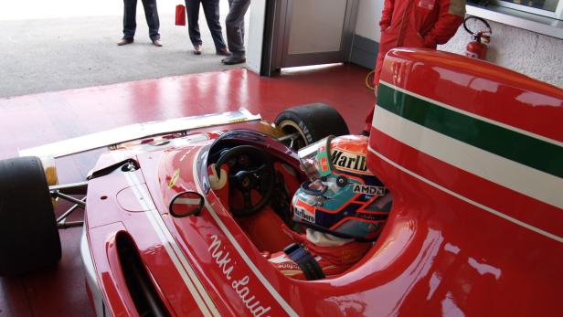 Ein roter Ferrari-Rennwagen mit der Aufschrift „Niki Lauda“ steht in einer Garage.
