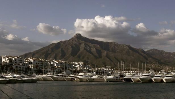 Blick auf einen Hafen mit Yachten und einem Berg im Hintergrund.