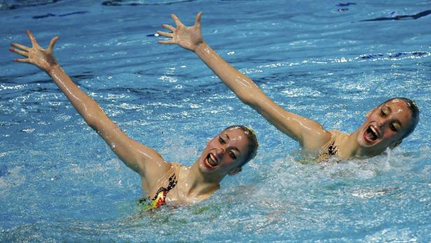 Zwei Synchronschwimmerinnen präsentieren eine Kür im Wasser.