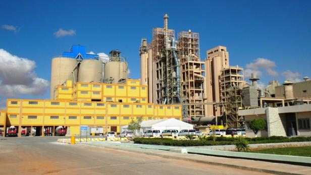 Eine große Industrieanlage mit gelben Gebäuden und Silos unter blauem Himmel.