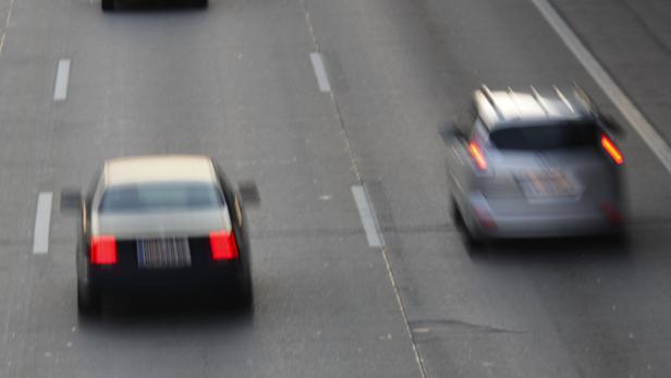 Zwei Autos fahren auf einer mehrspurigen Straße, beide sind unscharf in Bewegung zu sehen.