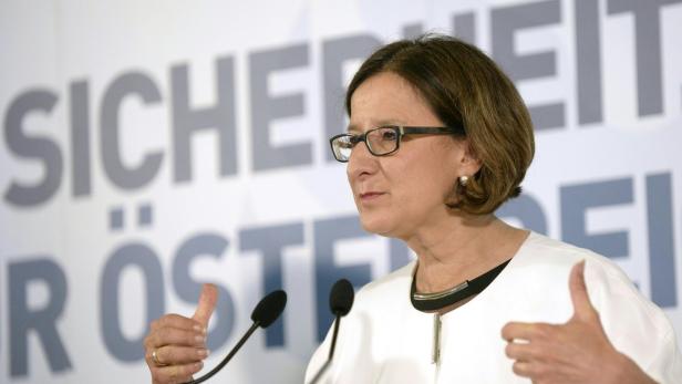 Eine Frau mit Brille gestikuliert vor dem Schriftzug „Sicherheit Österreich“.