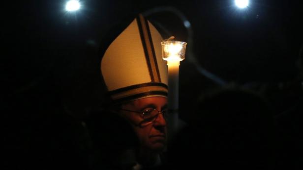 Papst Franziskus hält eine Kerze in der Hand.