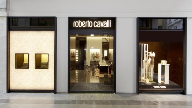 Die Fassade eines Roberto Cavalli Geschäfts mit Auslagen von Handtaschen und Kleidern.