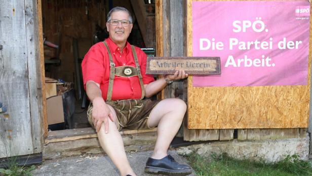 Reinhard Winterauer mit dem Originalschild des Arbeitervereins und einem alten SPÖ-Werbeplakat in seiner Holzhütte 