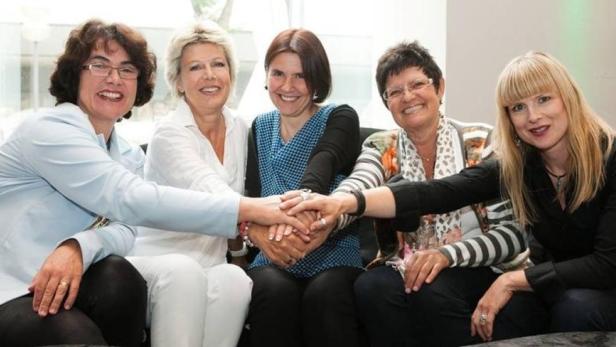 Fünf Frauen legen ihre Hände übereinander.