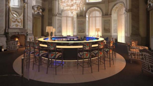 Ein runder Bartisch mit Stühlen in einem eleganten Raum mit Kamin und Kronleuchter.