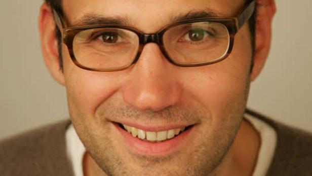 Ein lächelnder Mann mit Brille blickt in die Kamera.