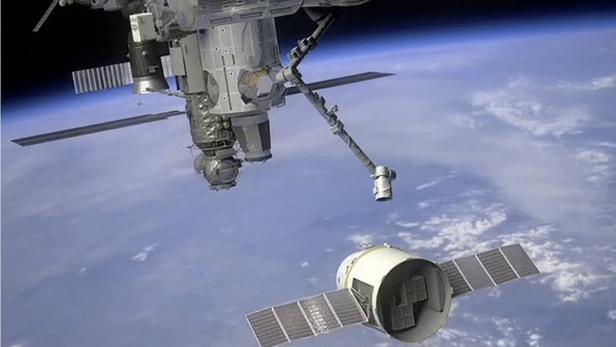 Die Internationale Raumstation über der Erde mit einem angedockten Raumschiff.