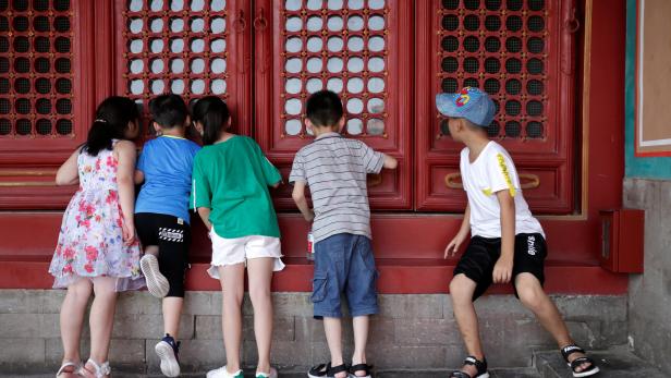 Children look inside through a window at the Forbidden City in central Beijing