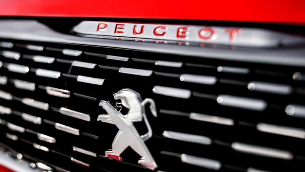 Nahaufnahme des Kühlergrills eines roten Peugeot mit dem Peugeot-Logo.
