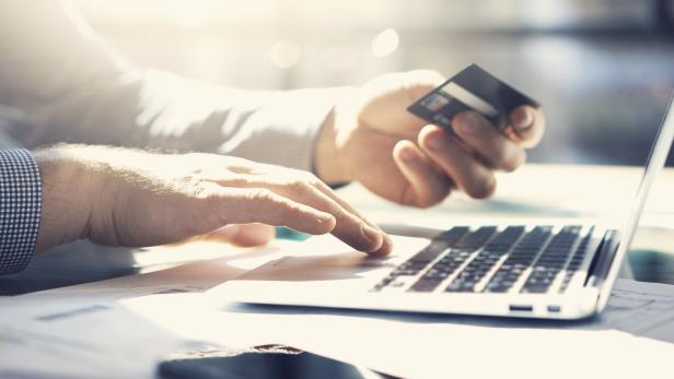 Ein Geschäftsmann arbeitet mit einem Laptop und hält eine Kreditkarte in der Hand. Online-Zahlungen werden getätigt.