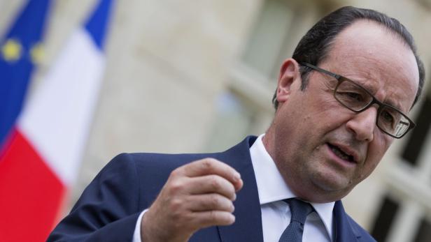 François Hollande spricht vor der französischen und europäischen Flagge.
