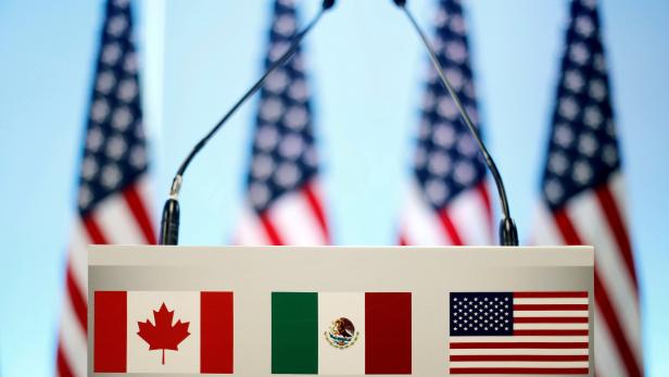 FILE PHOTO: The flags of Canada Mexico and the U.S. are seen on a lectern before a joint news conference of NAFTA talks in Mexico City