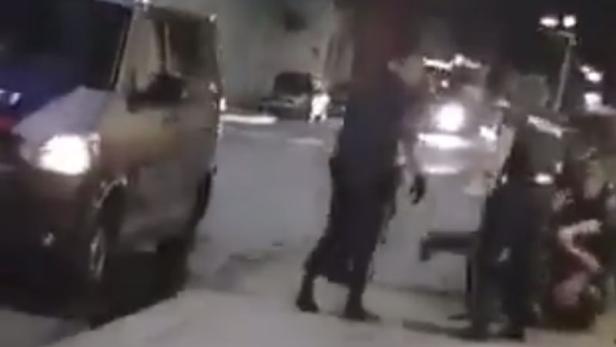 Polizisten nehmen eine Person auf der Straße fest.