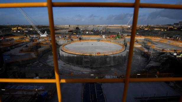 Blick durch ein Gitter auf eine Baustelle mit mehreren runden Fundamenten.