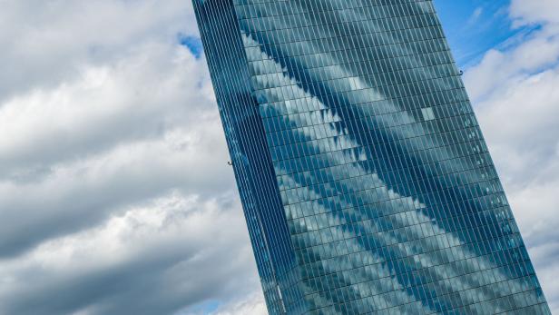 Ein modernes Hochhaus mit Glasfassade spiegelt den Himmel und die Wolken wider.