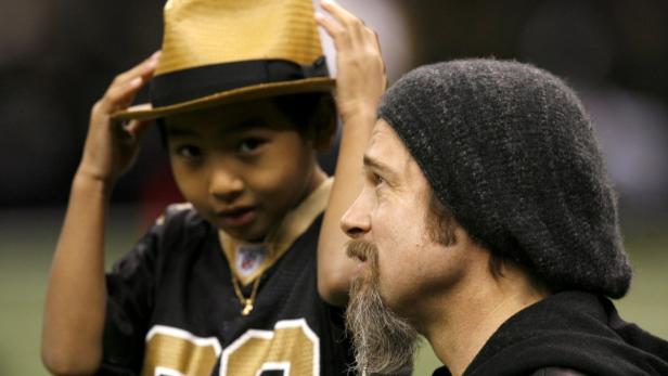 Actor Brad Pitt (R) and son Maddox stand on the field before play between the New Orleans Saints and the Arizona Cardinals in the NFL&#039;s NFC Divisional playoff football game in New Orleans, Louisiana January 16, 2010. REUTERS/Sean Gardiner (UNITED STATES - Tags: SPORT FOOTBALL ENTERTAINMENT)