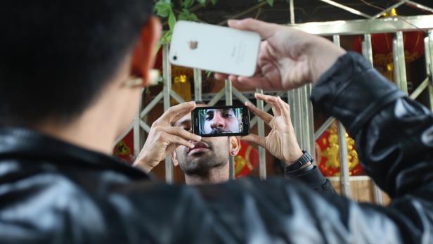 Eine Person macht mit einem Smartphone ein Foto von einer anderen Person, die ebenfalls ein Smartphone hält.