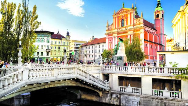 Blick auf die belebte Uferpromenade und die Franziskanerkirche in Ljubljana.